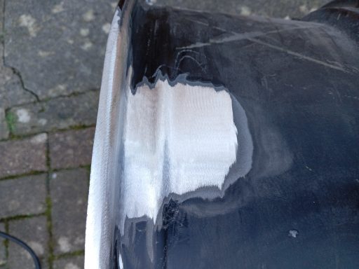 Close-up of a damaged metal surface showing a patch of repaired area.